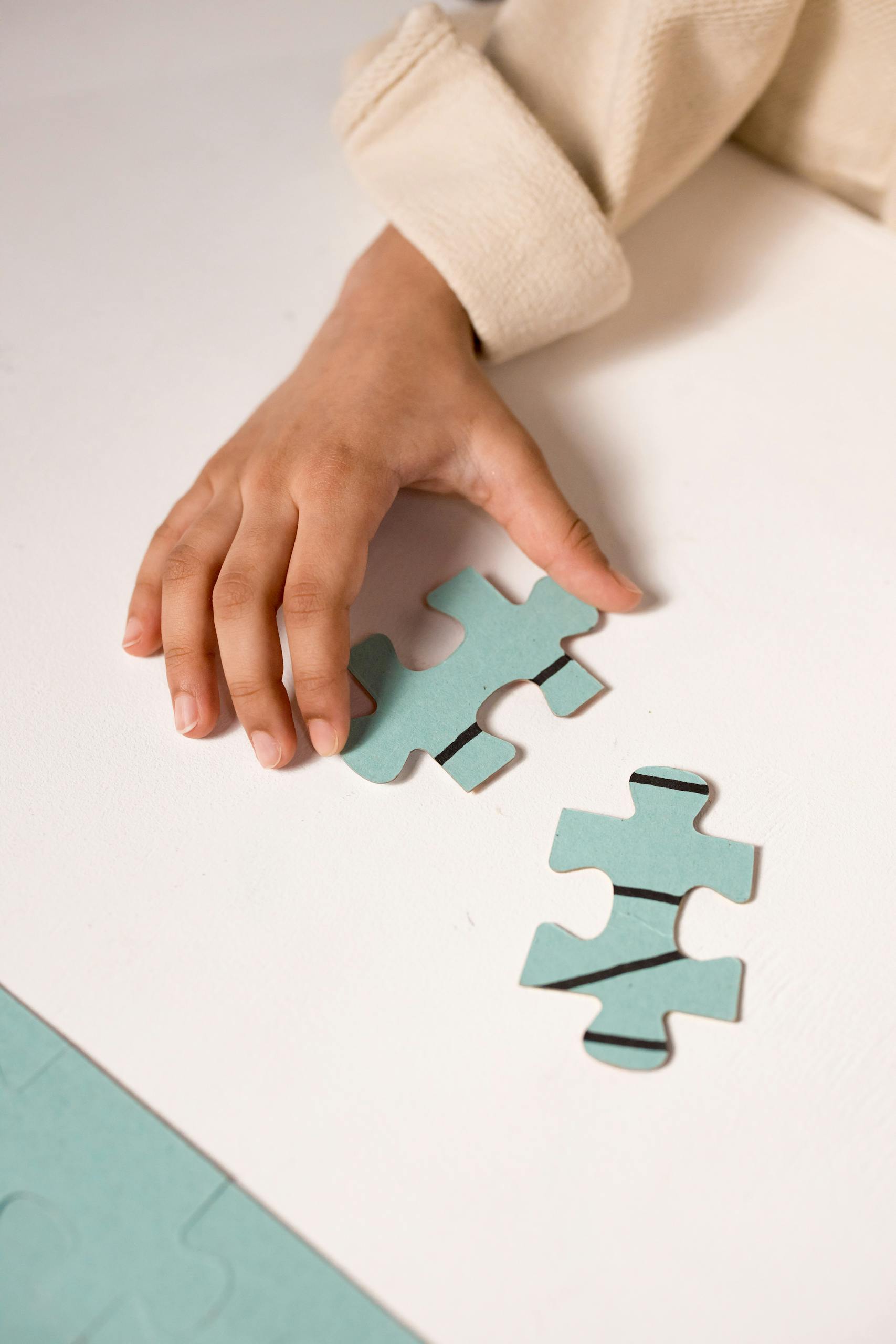 A child's hand in focus, solving a pastel blue puzzle, illustrating focus and learning.